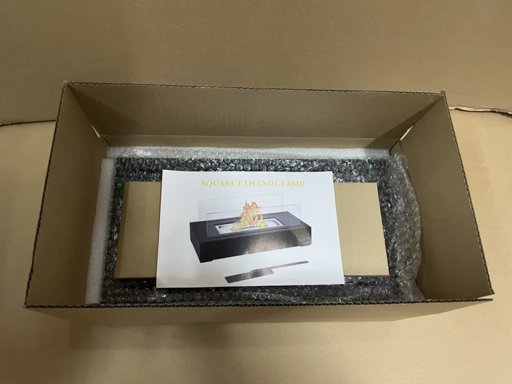 Open carton containing a protected tabletop fireplace and instruction sheet